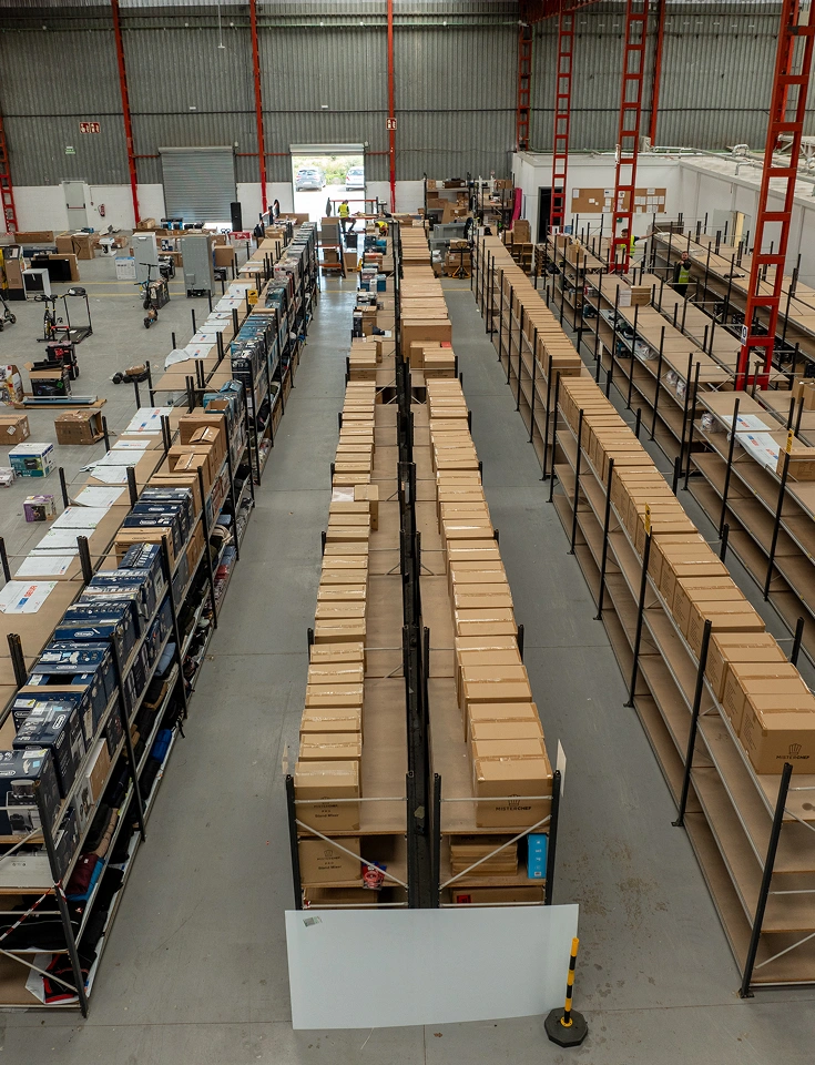 Zona de almacenaje de John Pye con estanterías metálicas y stock empaquetado